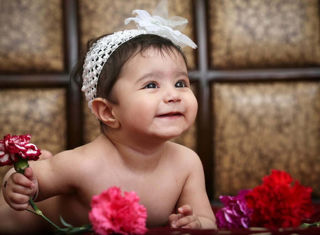 a baby with cute smile and colourful flower