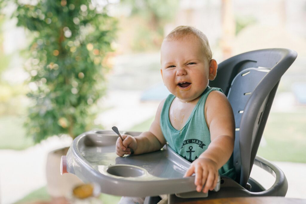 a small kid seating on a chair giving funny expressions